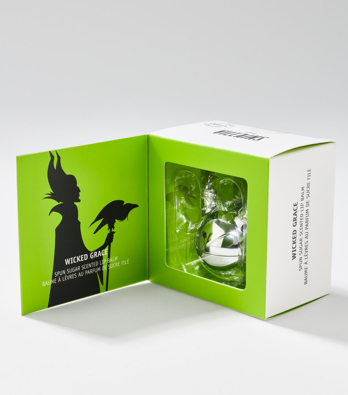 An open green and white gift box shows a silver lip balm in a clear window beside a black horned silhouette.