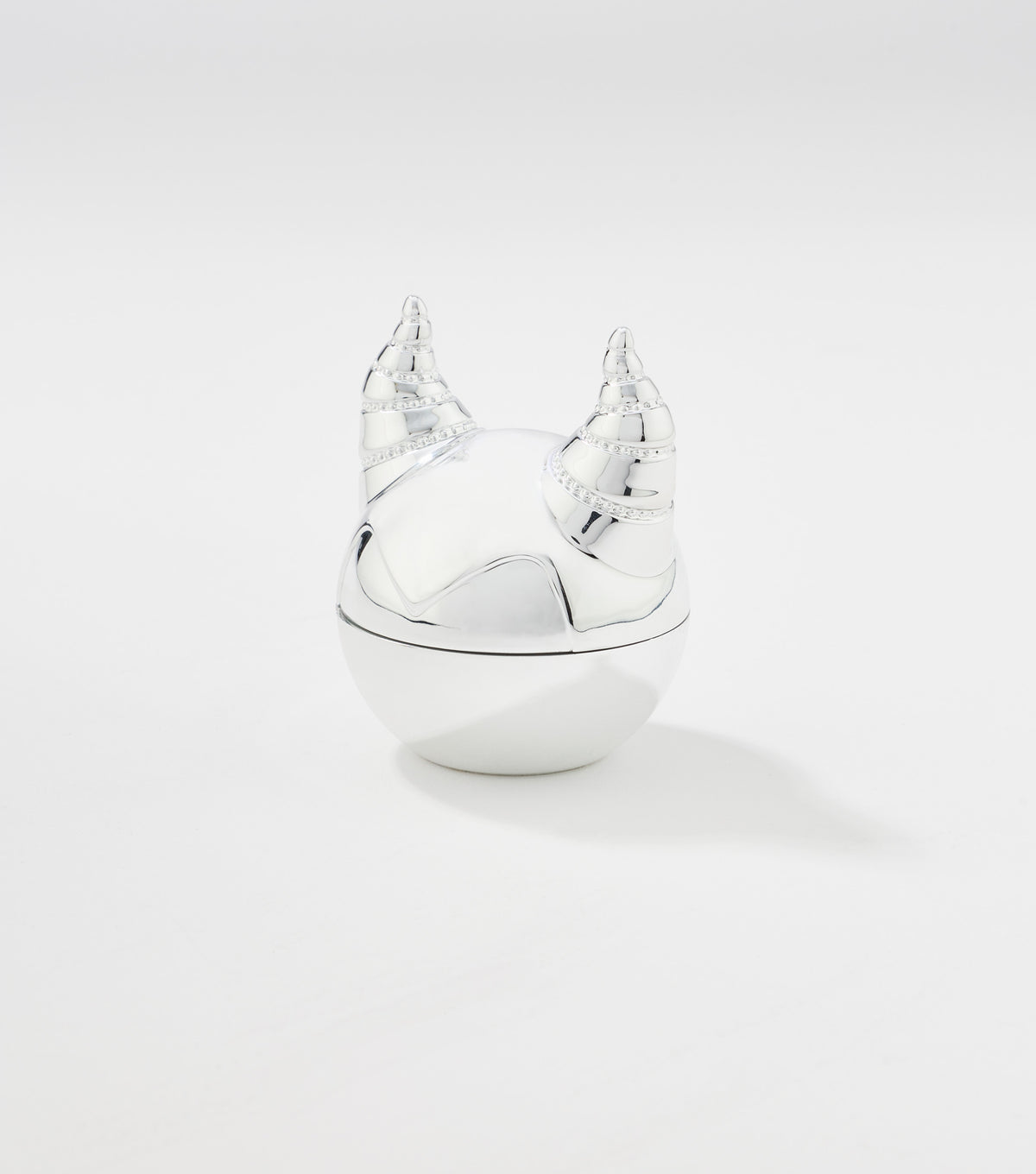 A round silver lip balm container with a glossy finish and a lid shaped like two curved, ridged horns.