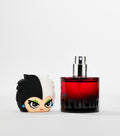 A red glass perfume bottle with a silver spray nozzle sits beside its black and white cartoon character head cap.