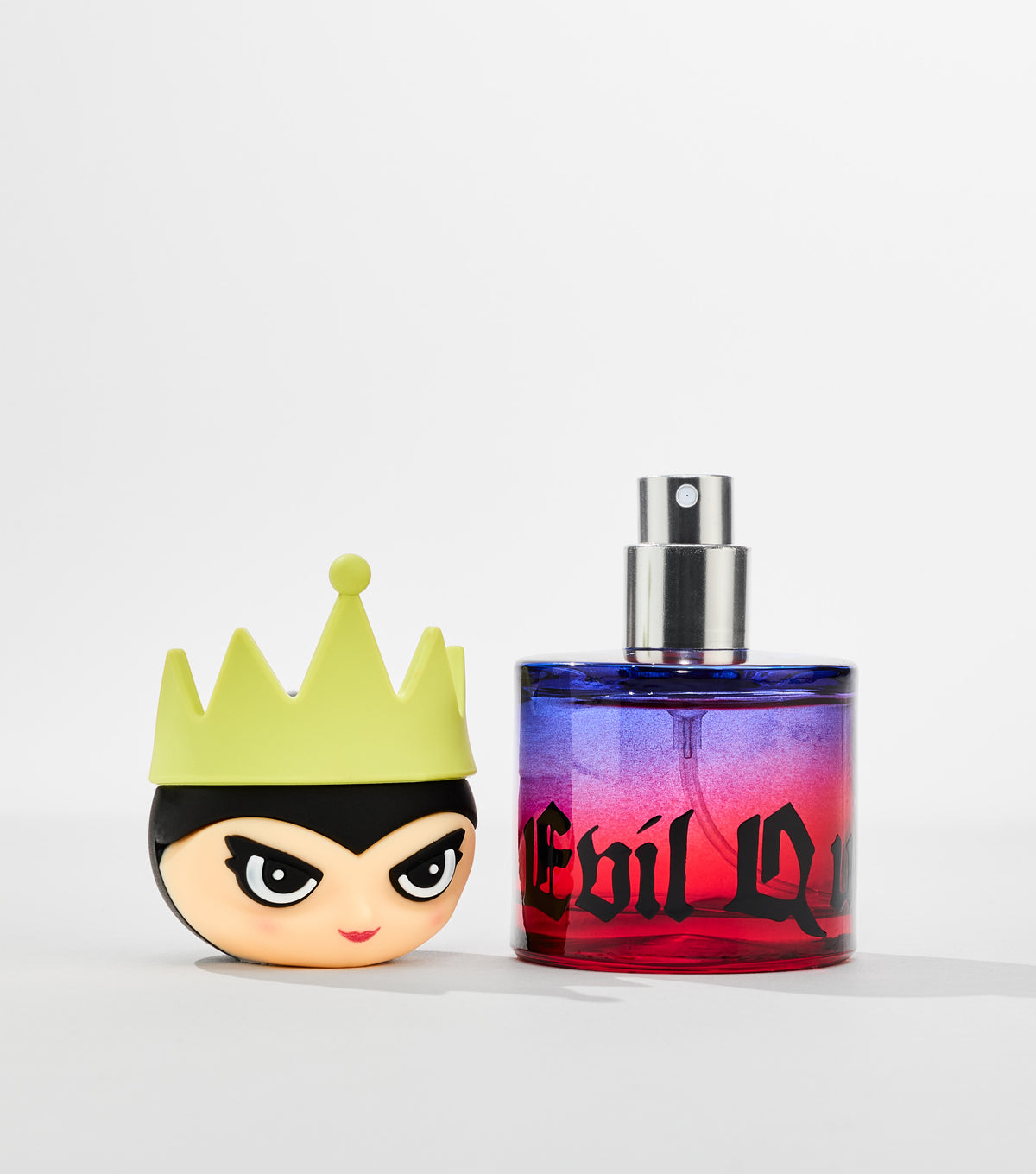 A purple-to-red gradient perfume bottle with gothic black lettering sits beside its cap shaped like a cartoon queen's head.