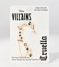 Gold-tone earrings and ear cuffs with black, red and clear stones, including a lipstick charm, are arranged on a white Disney Villains Cruella card.