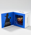 An open blue and white box shows a red and gold apple-shaped lip balm beside a black silhouette of a crowned queen.