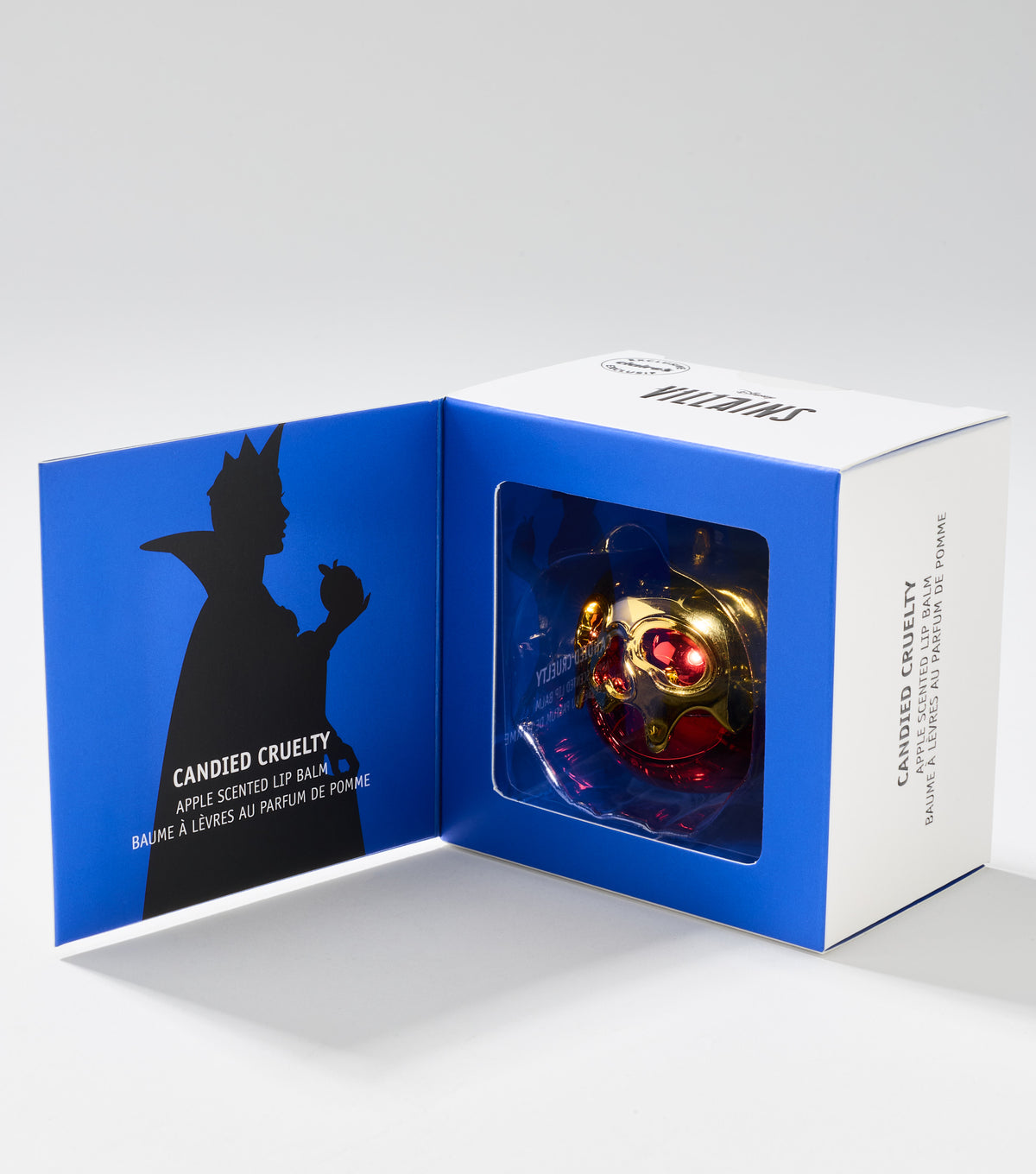 An open blue and white box shows a red and gold apple-shaped lip balm beside a black silhouette of a crowned queen.