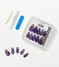 Purple almond-shaped press-on nails with gold charms and scale patterns sit in a clear case beside a nail file, glue, and stick.