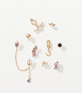 Ten gold-tone earrings with purple, clear and black gems, including a trident chain drop and a hoop with a tentacle charm.