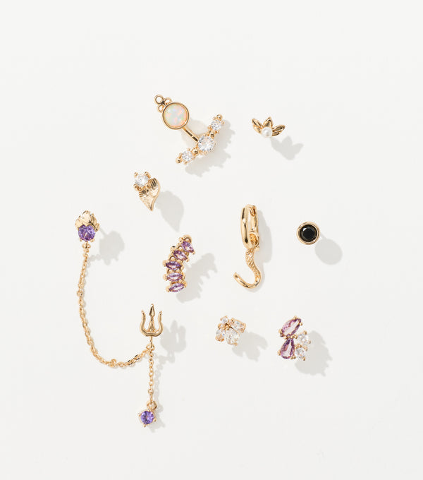 Ten gold-tone earrings with purple, clear and black gems, including a trident chain drop and a hoop with a tentacle charm.