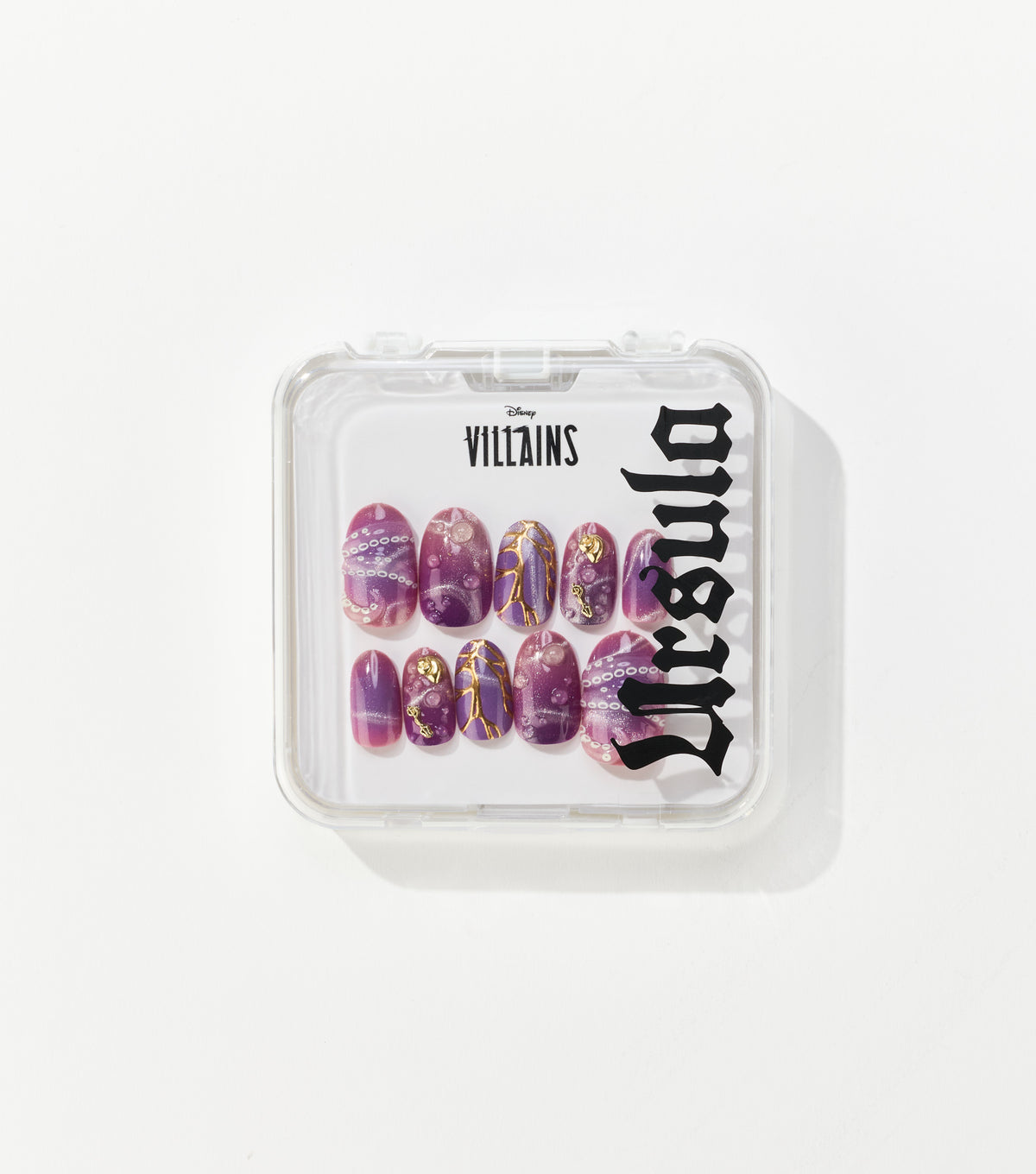A clear square case holds ten purple press-on nails with gold accents, white bubble details, and black Disney Villains Ursula lettering.
