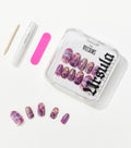 Purple press-on nails with gold accents in a clear Disney Villains Ursula case, beside a pink nail file, glue pen, and cuticle stick.