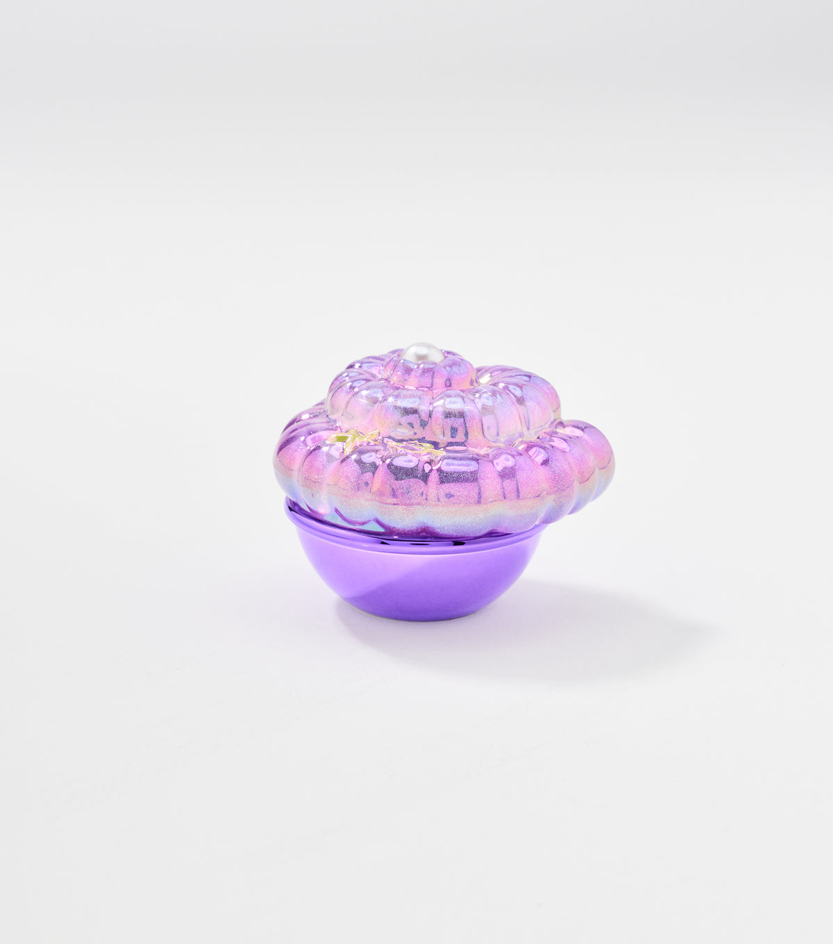 A shell-shaped lip balm container with an iridescent pink and purple lid, a small pearl on top, and a metallic purple base.