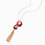 Long collier anneaux rouges avec pompon couleur dor&eacute;e,